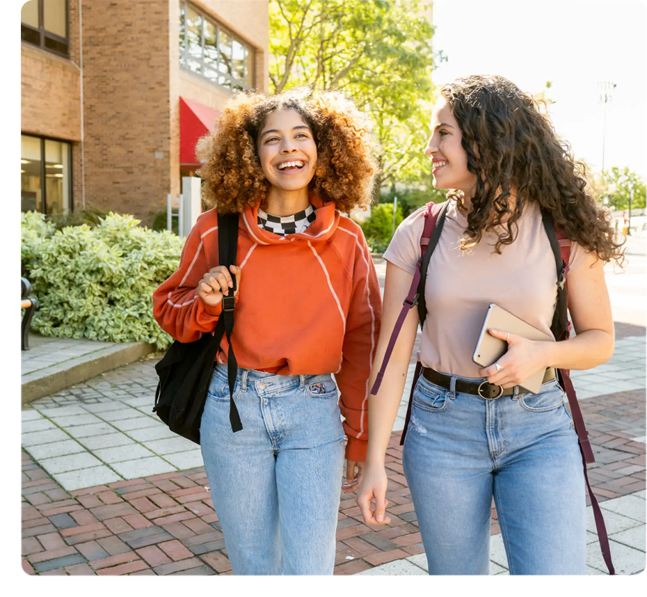 Two women walking and smiling outdoors.