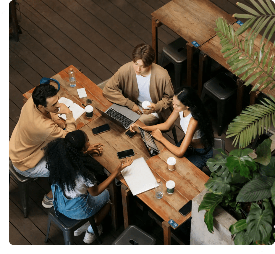Group collaborating at a wooden table, overhead view.
