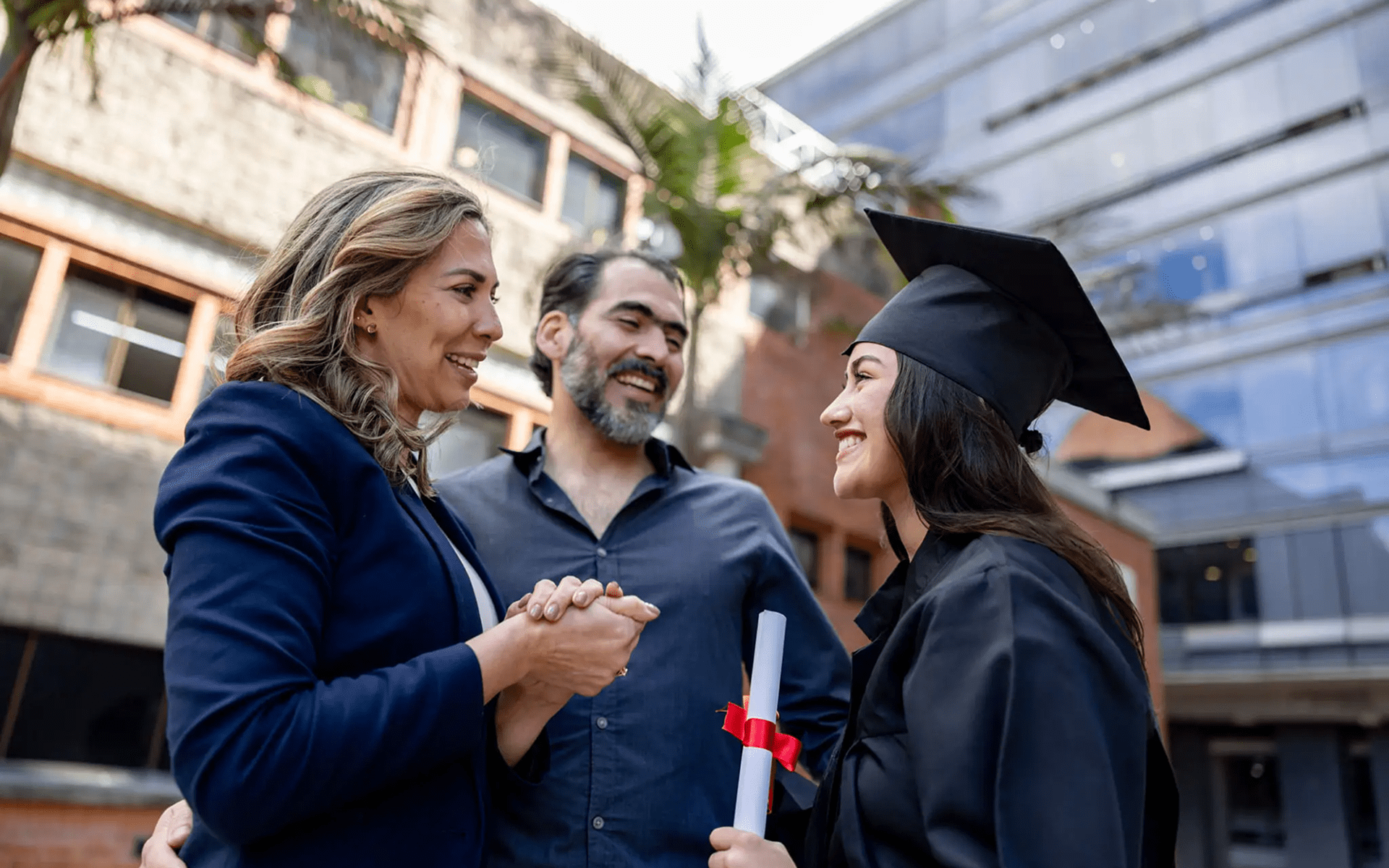Graduate celebrating with family, holding diploma.